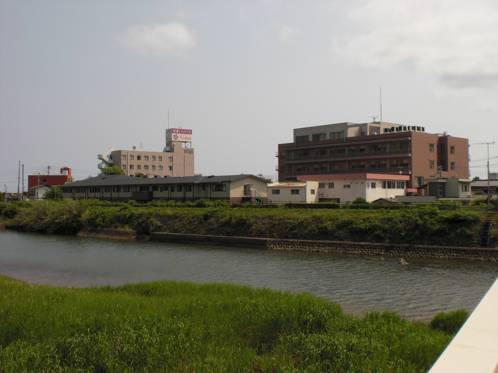 河川沿いに立つ介護施設の外観。複数棟の建物が見える。