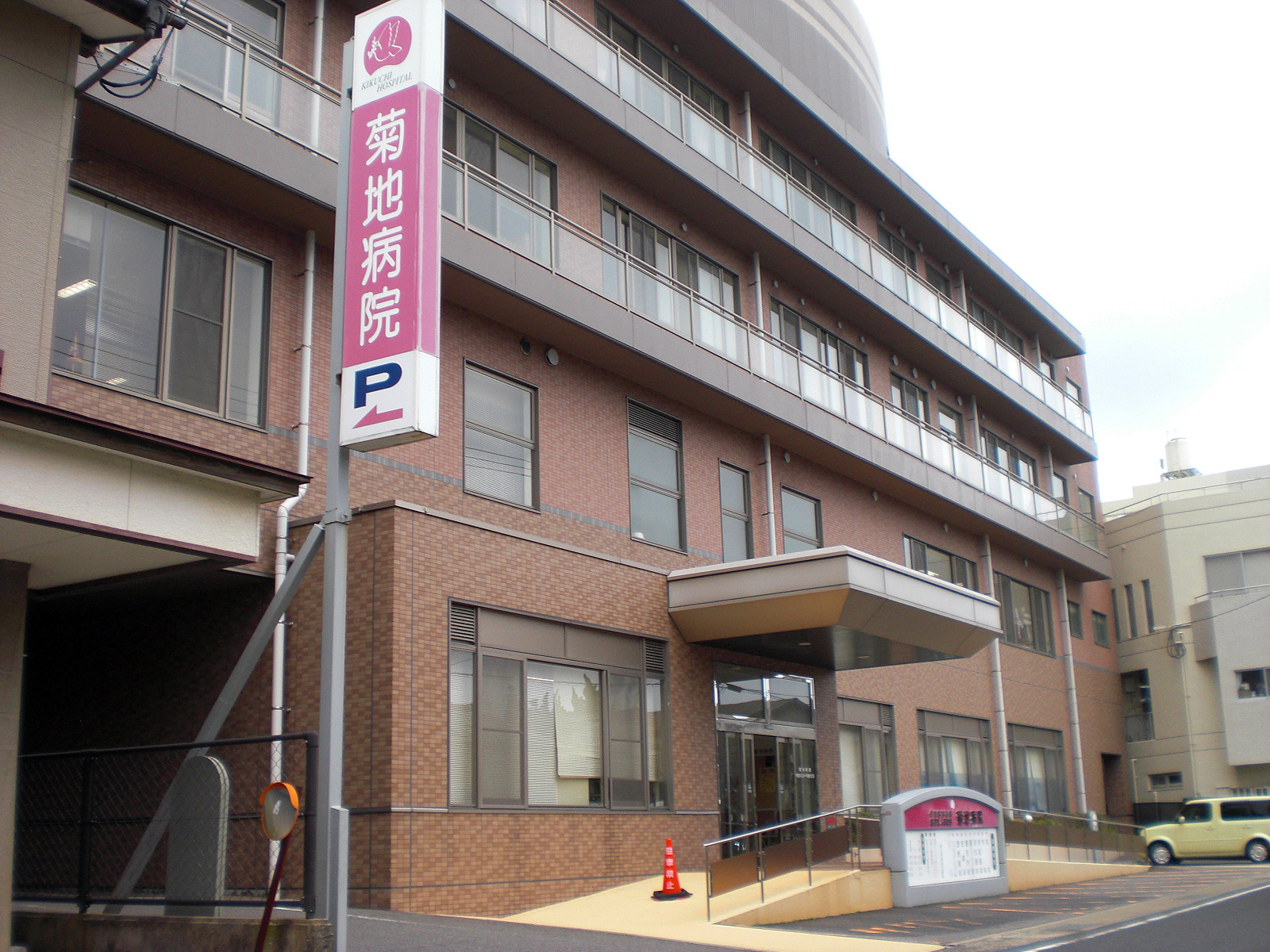 菊地病院の建物外観。赤レンガ造りの多階建て医療施設で、玄関前にシンボル看板がある。